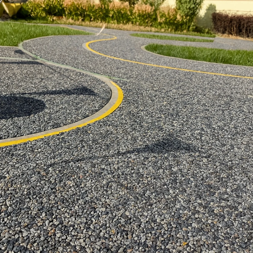 Curved grey resin-bound walkway in a community landscape, demonstrating permeability, everyday usage patterns, and system-level pavement performance.
