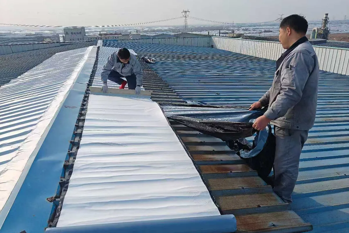 Installer peeling the release liner as radiative cooling film is pressed onto a metal roof