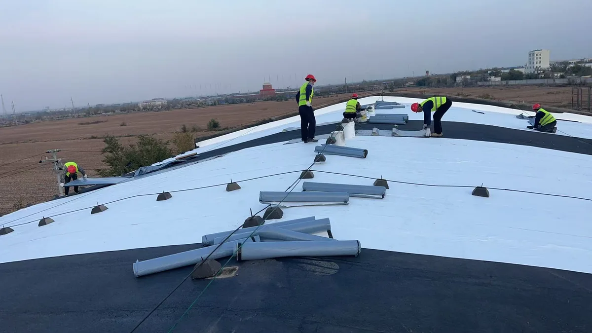 Large curved roof covered with white radiative cooling film during installation